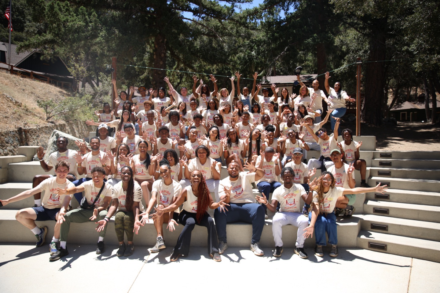 Large group of MTS participants and staff at camp, seated on outdoor bleachers